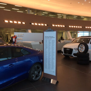 RIGiD Sign in the shape of a clipboard next to a car at Audi dealership
