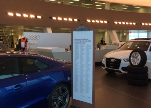 RIGiD Sign in the shape of a clipboard next to a car at Audi dealership