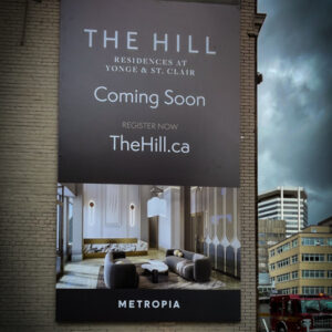 Frameless Metropia The Hill Frameless sign on brick wall