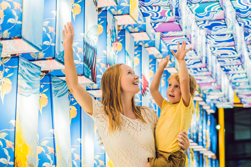 photo of mom holding up child to see colourful displays